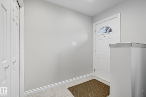 Entryway featuring a white paneled door with an arched window, light gray walls, and light-toned tile flooring - 14239 53 Street, Edmonton, AB 