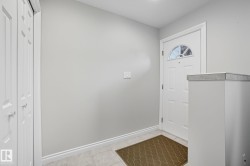 Entryway featuring a white paneled door with an arched window, light gray walls, and light-toned tile flooring - 