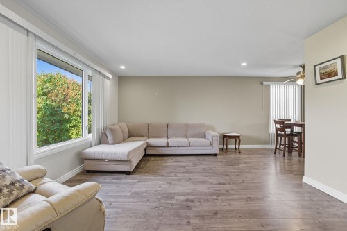 Open living area featuring wood-finish flooring, recessed lighting, and large windows - 14239 53 Street, Edmonton, AB 