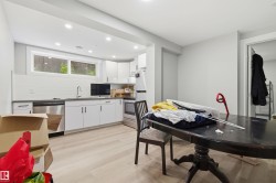 Modern kitchen featuring white cabinetry, stainless steel appliances, light wood-finish flooring, recessed lighting, and a subway tile backsplash - 