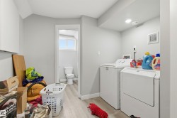 Dedicated laundry area featuring light wood-finish flooring, light gray wall paint, recessed lighting, and a white baseboard trim - 