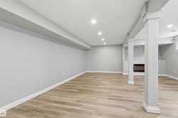 Finished lower level featuring wood-finish flooring, recessed lighting, and support columns with decorative trim - 