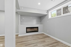 Recessed electric fireplace with a built-in media niche, wood-finish flooring, and a large egress window - 