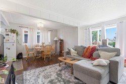 Living room featuring wood-finish flooring, white trim, and ample natural light from multiple windows - 