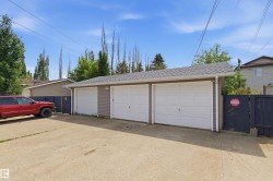 Triple-bay detached garage featuring light gray siding, white garage doors, and a shingled roof - 