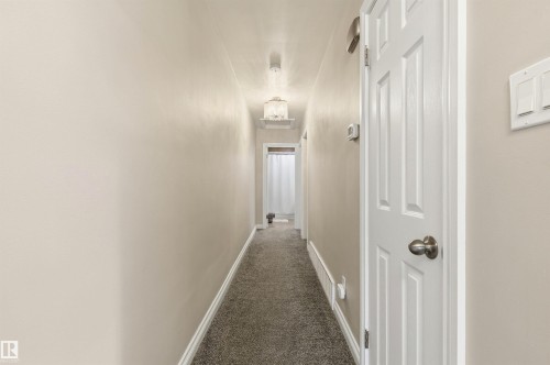 Carpeted hallway with light neutral wall paint and white baseboards - 7412/7414 83 Avenue, Edmonton, AB 