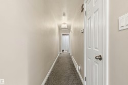 Carpeted hallway with light neutral wall paint and white baseboards - 