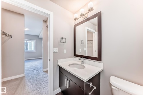 Bathroom vanity featuring a dark wood cabinet, white countertop, undermount sink, and brushed nickel faucet - 303 560 Griesbach Parade Parade, Edmonton, AB 