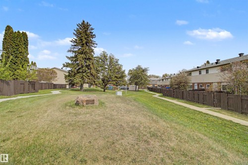 Expansive green space featuring a walking path, mature trees, and a commemorative stone - 5724 143 Avenue, Edmonton, AB 