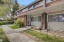 Brick and siding exterior featuring multiple large windows, a covered entryway, and a concrete pathway - 5724 143 Avenue, Edmonton, AB 