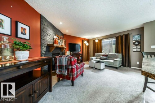 Living area featuring a stone accent wall with a fireplace and mantel, recessed lighting, and a large window - 8507 2 Avenue, Edmonton, AB - Indoor