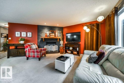 Living area featuring a textured stone-finish accent wall with a wood mantel, a built-in fireplace, and recessed ceiling lighting - 8507 2 Avenue, Edmonton, AB - Indoor Photo Showing Living Room With Fireplace