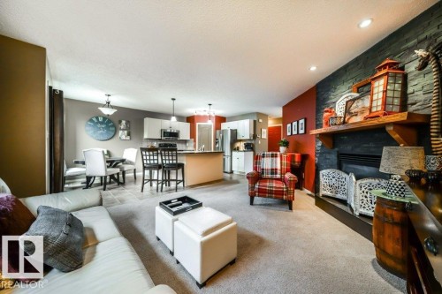 Spacious living area featuring a stone accent wall with a built-in fireplace, a wood mantel, and recessed lighting - 8507 2 Avenue, Edmonton, AB - Indoor Photo Showing Living Room