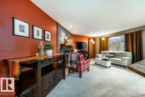 Open-concept living area featuring a stone accent wall and a built-in fireplace - 8507 2 Avenue, Edmonton, AB - Indoor