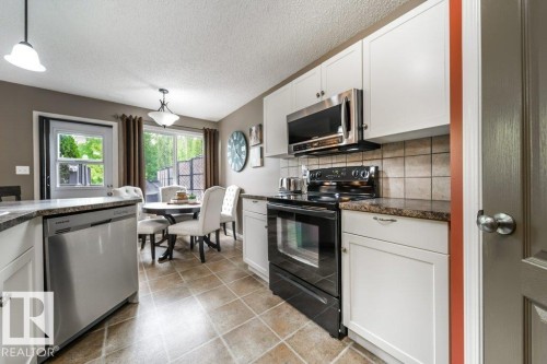 Kitchen featuring white cabinetry, stainless steel appliances, and tile flooring - 8507 2 Avenue, Edmonton, AB - Indoor Photo Showing Kitchen