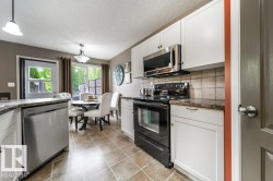 Kitchen featuring white cabinetry, stainless steel appliances, and tile flooring - 