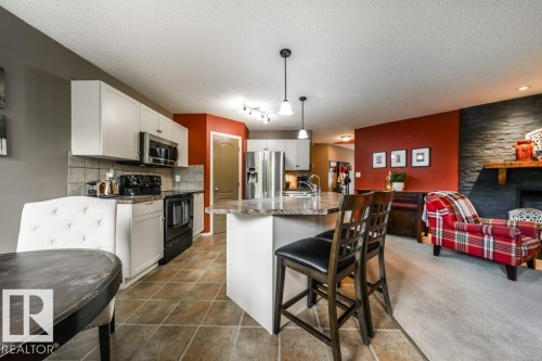 Kitchen featuring white cabinetry, stainless steel appliances, and a central island with an integrated breakfast bar - 8507 2 Avenue, Edmonton, AB - Indoor