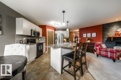 Kitchen featuring white cabinetry, stainless steel appliances, and a central island with an integrated breakfast bar - 