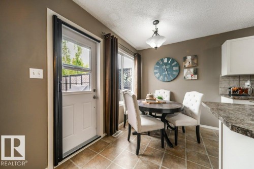 Dining area featuring tile flooring, a white exterior door with glass insert, and a window with dark curtain rods - 8507 2 Avenue, Edmonton, AB - Indoor Photo Showing Dining Room