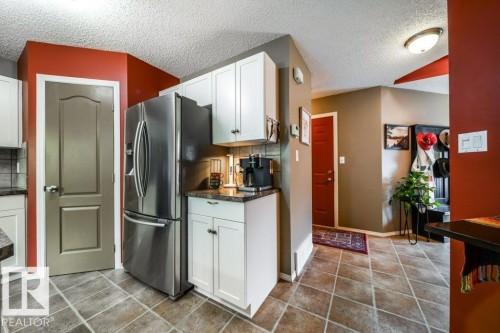 Kitchen area with white cabinetry, stainless steel refrigerator, and dark countertops - 8507 2 Avenue, Edmonton, AB - Indoor Photo Showing Kitchen