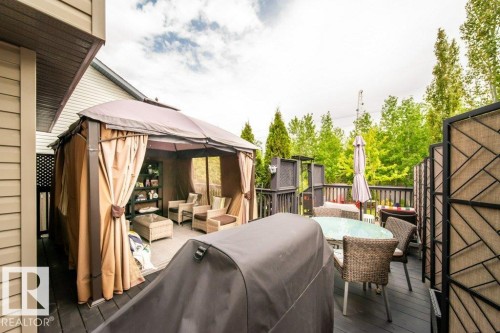 Expansive dark-toned deck featuring a covered gazebo with privacy curtains, a decorative privacy screen, and a glass-top dining table - 8507 2 Avenue, Edmonton, AB - Outdoor With Deck Patio Veranda With Exterior