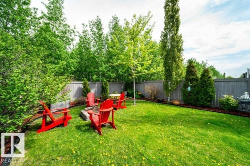 Expansive fenced backyard featuring a lush green lawn, mature trees, and a dedicated fire pit area - 8507 2 Avenue, Edmonton, AB - Outdoor