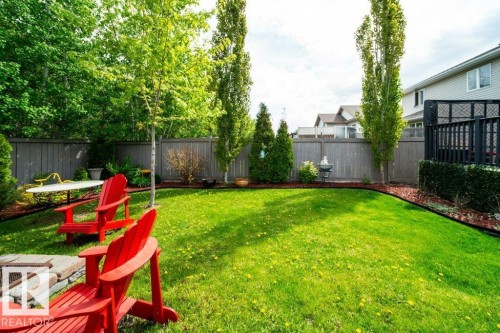 Expansive backyard featuring a lush lawn, mature trees, a privacy fence, and a built-in stone fire pit - 8507 2 Avenue, Edmonton, AB - Outdoor With Backyard