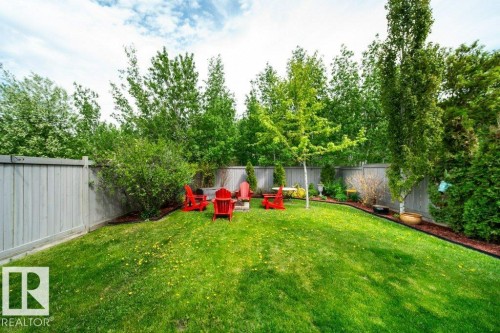Expansive backyard featuring a manicured lawn, established trees, and a wooden privacy fence - 8507 2 Avenue, Edmonton, AB - Outdoor With Backyard