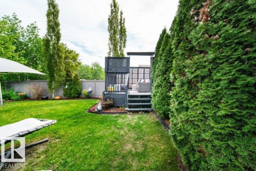 Manicured lawn with a multi-level deck featuring dark grey wood-finish railing and lattice details - 8507 2 Avenue, Edmonton, AB - Outdoor