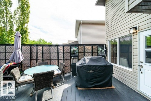 Spacious exterior deck with dark wood-finish flooring, featuring a decorative privacy screen, light-colored siding, and an exterior wall lantern - 8507 2 Avenue, Edmonton, AB - Outdoor With Deck Patio Veranda With Exterior