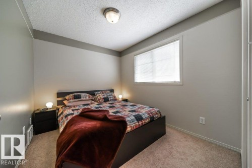 Neutral-toned bedroom featuring wall-to-wall carpeting, a horizontal window with blinds, and a built-in ceiling light fixture - 8507 2 Avenue, Edmonton, AB - Indoor Photo Showing Bedroom