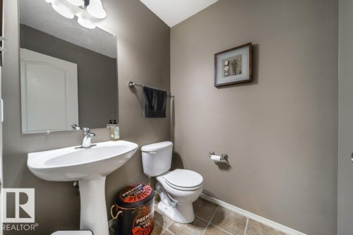 Pedestal sink with chrome faucet, complemented by a wall-mounted mirror and overhead vanity lighting - 8507 2 Avenue, Edmonton, AB - Indoor Photo Showing Bathroom