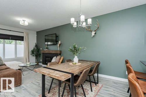 Open-concept living area featuring wood-finish flooring, a wall-mounted fireplace with a rustic wood mantel, and a dedicated dining space - 721 Berg Loop, Leduc, AB - Indoor Photo Showing Dining Room With Fireplace