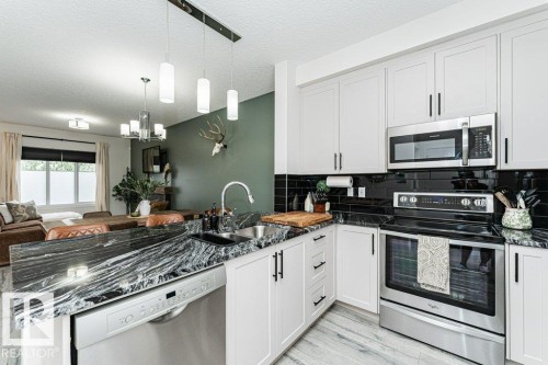 Modern kitchen featuring white shaker cabinetry with dark hardware, stainless steel appliances, black subway tile backsplash, and a patterned dark countertop - 721 Berg Loop, Leduc, AB - Indoor Photo Showing Kitchen With Stainless Steel Kitchen With Double Sink With Upgraded Kitchen