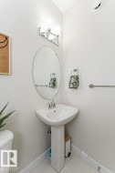 Pedestal sink with chrome faucet, an oval vanity mirror, and an overhead vanity light fixture - 