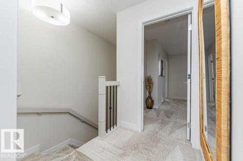 Carpeted staircase with white balusters and black metal spindles - 721 Berg Loop, Leduc, AB - Indoor Photo Showing Other Room