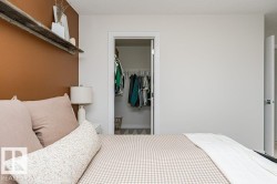 Bedroom featuring an accent wall, a wall-mounted rustic wood shelf, and a walk-in closet with wire shelving - 