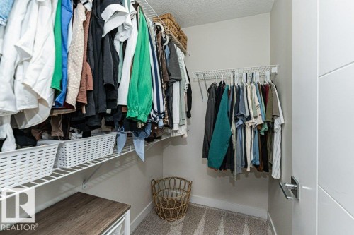 Walk-in closet featuring wire shelving, multiple hanging rods, and a light-colored carpet - 721 Berg Loop, Leduc, AB - Indoor With Storage