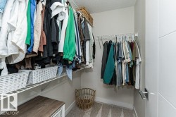 Walk-in closet featuring wire shelving, multiple hanging rods, and a light-colored carpet - 