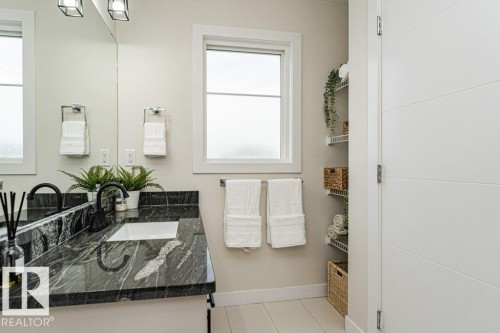 Bathroom vanity featuring a dark patterned countertop with an integrated white rectangular sink and a matte black single-handle faucet - 721 Berg Loop, Leduc, AB - Indoor Photo Showing Bathroom