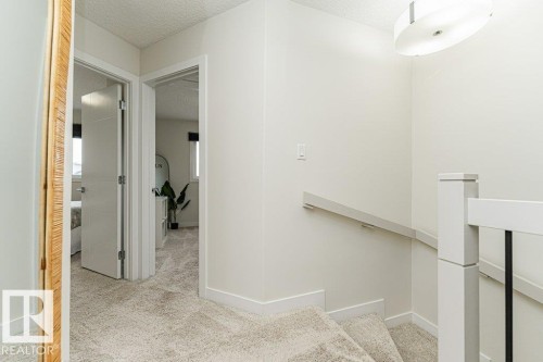Upper landing with light-toned wall finishes and textured carpeting - 721 Berg Loop, Leduc, AB - Indoor