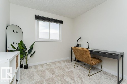 Bright room featuring clean white walls, window with black blinds, textured neutral carpeting, and white baseboards - 721 Berg Loop, Leduc, AB - Indoor
