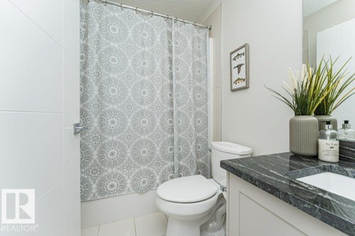Bathroom featuring a single vanity with a dark, patterned countertop, an integrated sink, and a large mirror - 721 Berg Loop, Leduc, AB - Indoor Photo Showing Bathroom