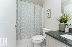 Bathroom featuring a single vanity with a dark, patterned countertop, an integrated sink, and a large mirror - 