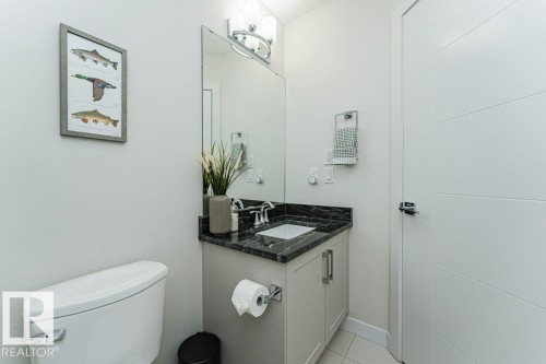 Bathroom featuring a vanity with a dark stone countertop, an integrated rectangular sink, and chrome fixtures - 721 Berg Loop, Leduc, AB - Indoor Photo Showing Bathroom