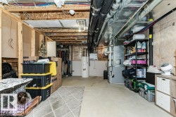 Unfinished basement space featuring exposed wooden framing, visible ductwork, and electrical conduits - 