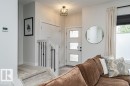 Entryway featuring a three-panel opaque glass door, a black metal cage ceiling light fixture, a staircase with white newel posts and black metal spindles, and light-colored carpeting - 721 Berg Loop, Leduc, AB  - Indoor 