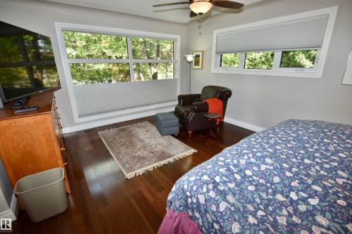 Expansive window with privacy shades, wood-finish flooring, light gray wall paint, white baseboards, and a ceiling fan with integrated lighting - 6 St George'S Crescent, Edmonton, AB 