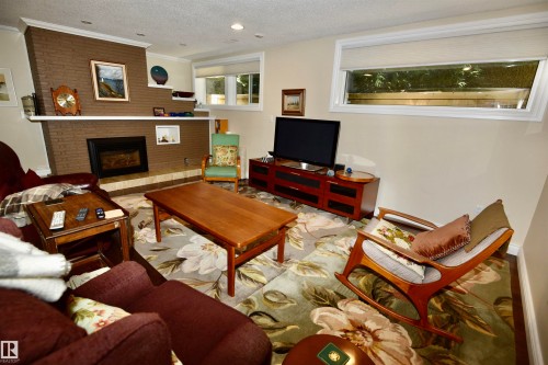 Spacious rumpus room featuring a prominent brick fireplace with a white mantel, recessed lighting, and light-toned walls - 6 St George'S Crescent, Edmonton, AB 