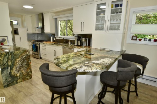 Kitchen featuring stone countertops, white cabinetry, stainless steel appliances, and wood-finish flooring - 6 St George'S Crescent, Edmonton, AB 